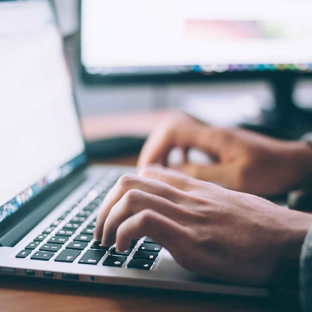 Hands typing on a laptop keyboard